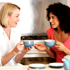 two women talking, two women smiling, two women drinking cup of coffee or tea